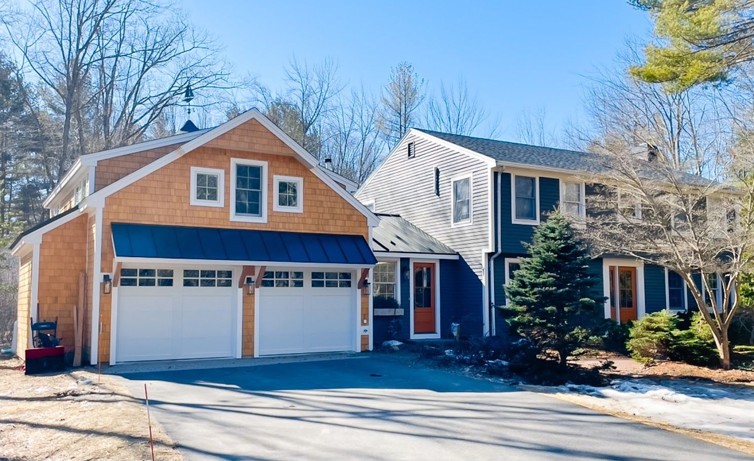 Suburban house with a two-car garage, tan siding, and white trim on a sunny day