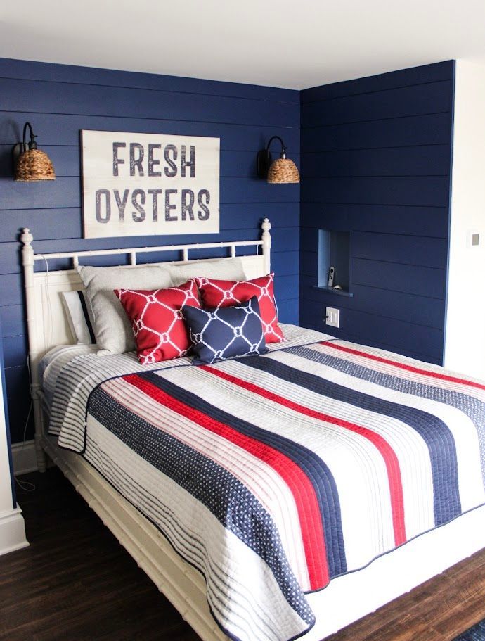 Coastal bedroom with navy walls, white bed, red-white-blue striped bedding, and “Fresh Oysters” sign