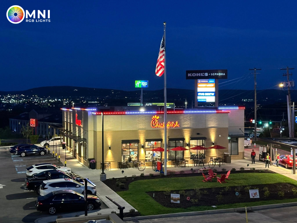 Nighttime exterior of a Buc-ee’s convenience store with bright lights, parked cars, and a tall American flag