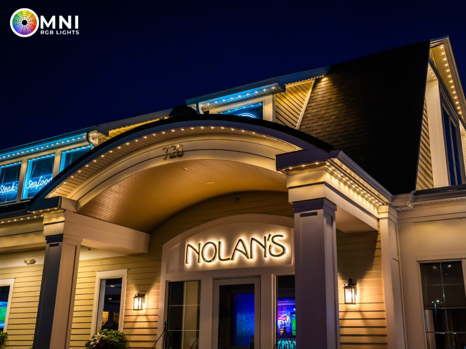 Nighttime exterior of Nolan’s restaurant with glowing entrance and blue-lit roofline