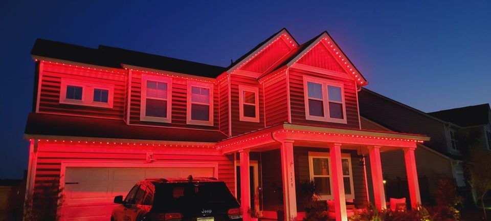 Two-story house lit in red at night under a dark sky