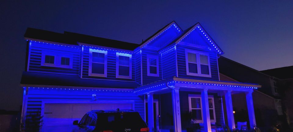 Two-story house lit with bright blue holiday lights at night