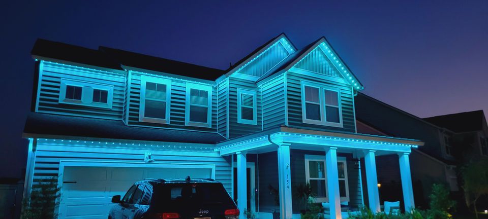 Two-story house lit with bright blue accent lights at night