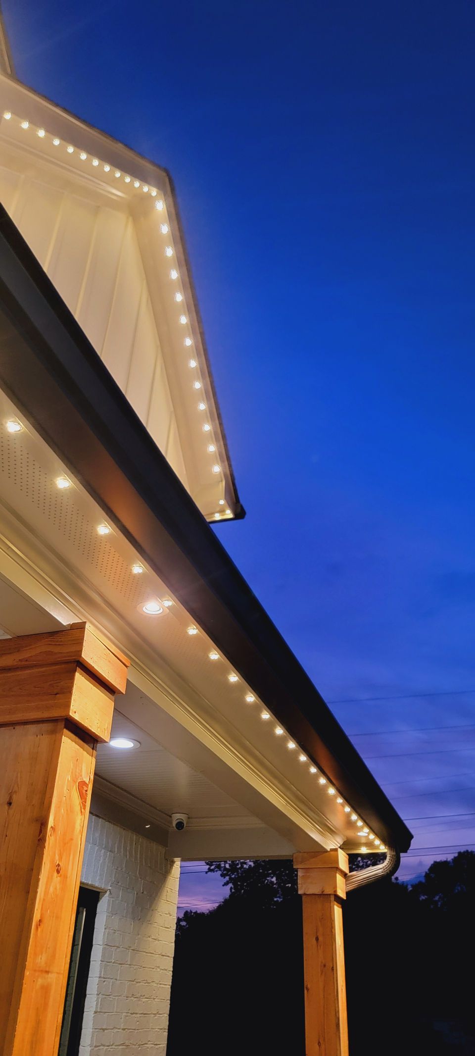 Lit house roofline with warm string lights against a deep blue evening sky