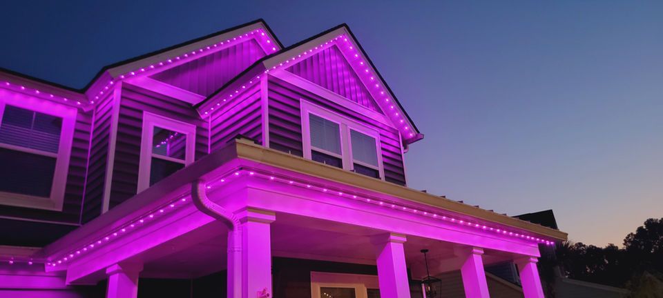 House outlined with bright purple lights at dusk