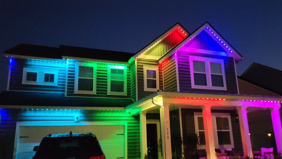 Two-story house lit with colorful rainbow LED lights at night