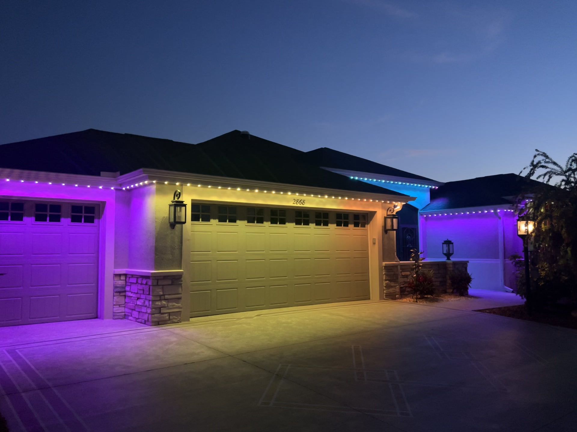 Single-story house exterior with purple and warm yellow accent lighting at night