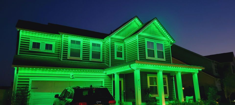 Two-story house lit with bright green lights at night