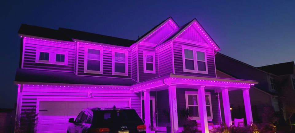 Two-story house lit in bright purple lights at dusk