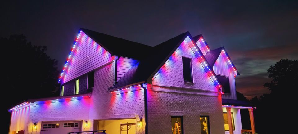 House at night lit with purple and pink LED lights against a dark sky