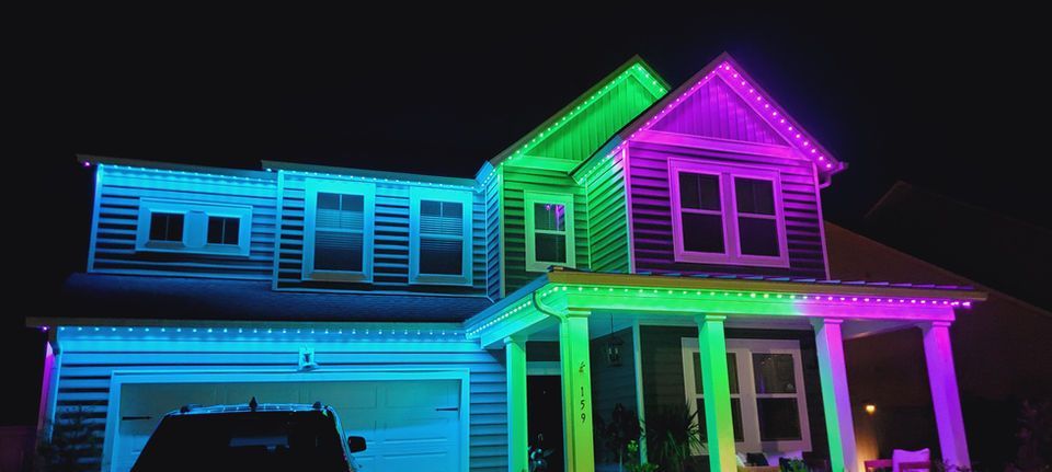 House outlined with blue, green, and pink neon lights at night