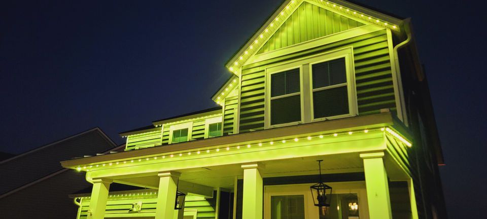House outlined in bright yellow lights at night against a dark sky