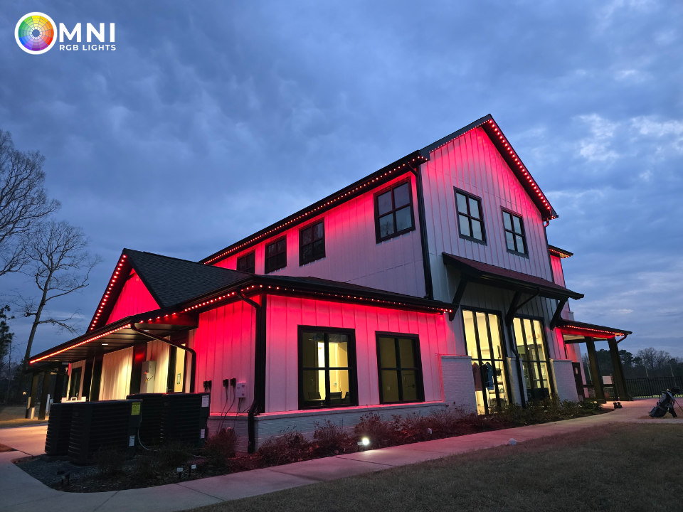 Two-story modern farmhouse with pink-lit exterior at dusk under a cloudy sky