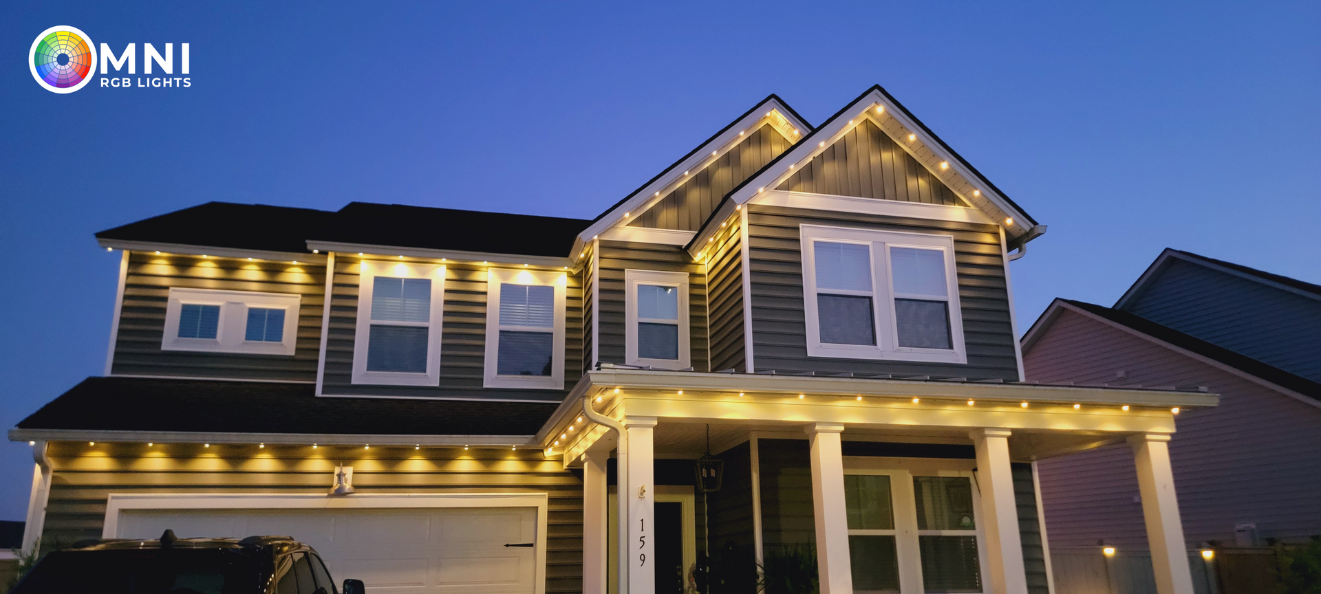 Two-story house with lit exterior trim at dusk and a two-car garage