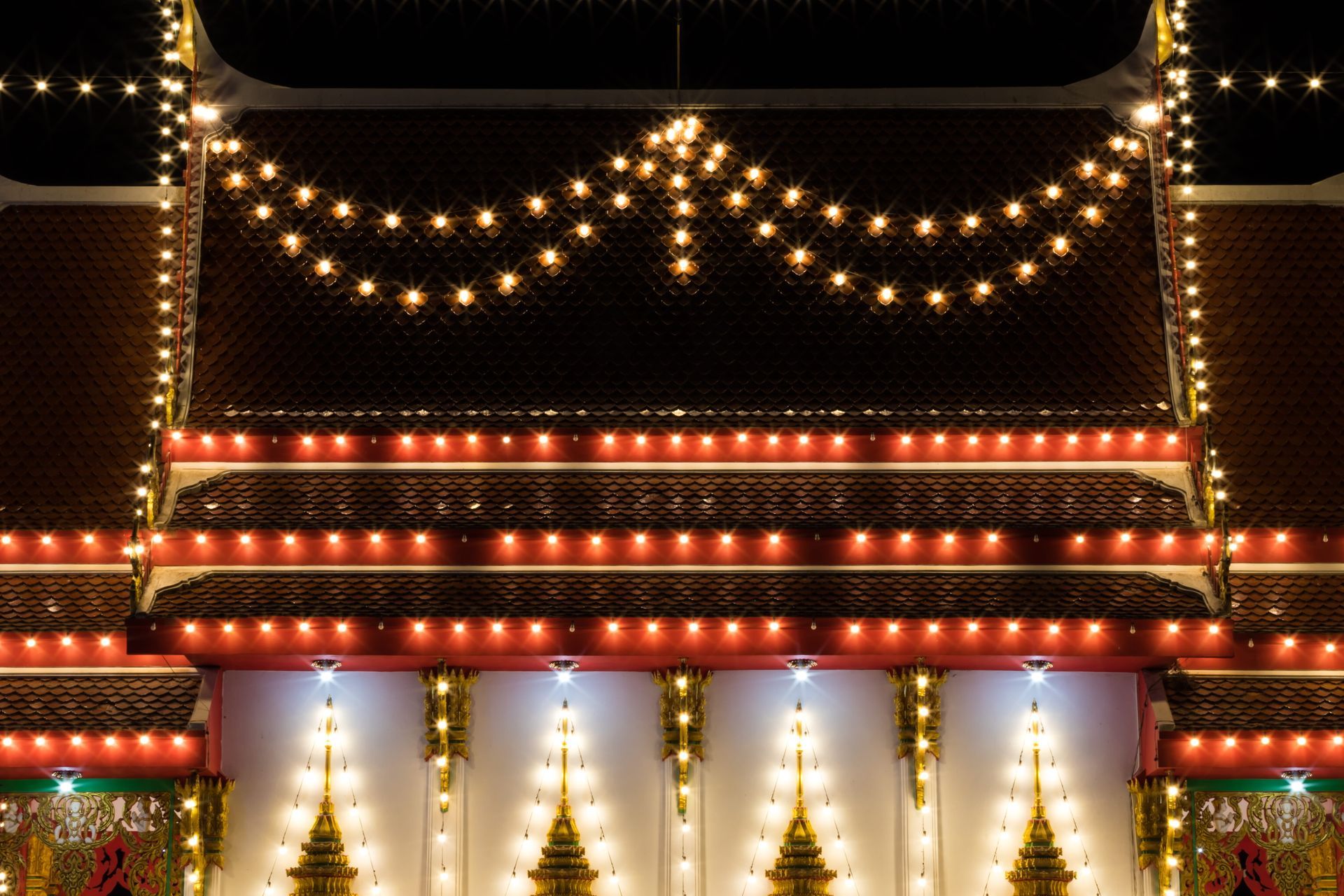 Festive building facade with strings of warm white and red lights at night