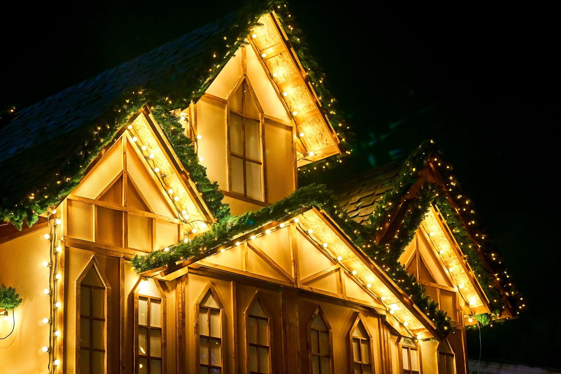 Warmly lit house decorated with golden holiday lights at night