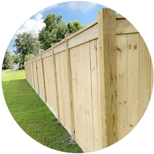 Wooden fence along green grass under a blue sky.