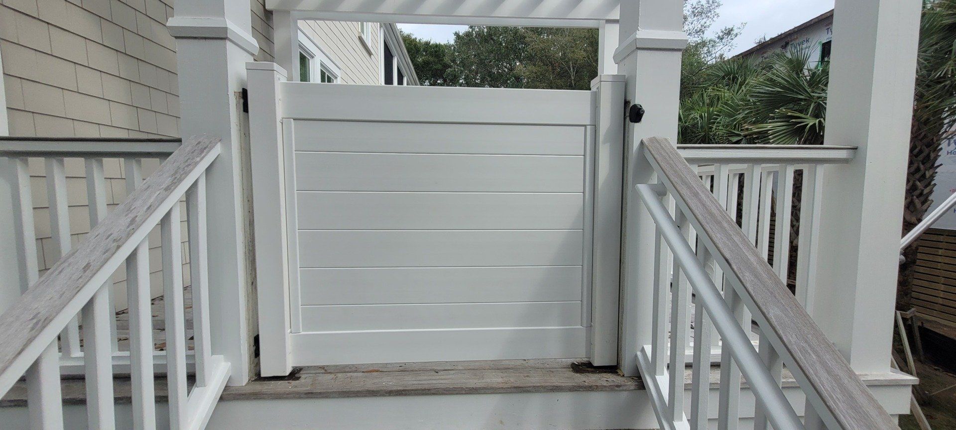 White wooden gate on a porch with stairs and railings.