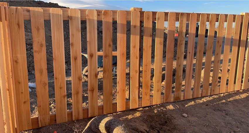 Wooden picket fence in a sunny outdoor setting.