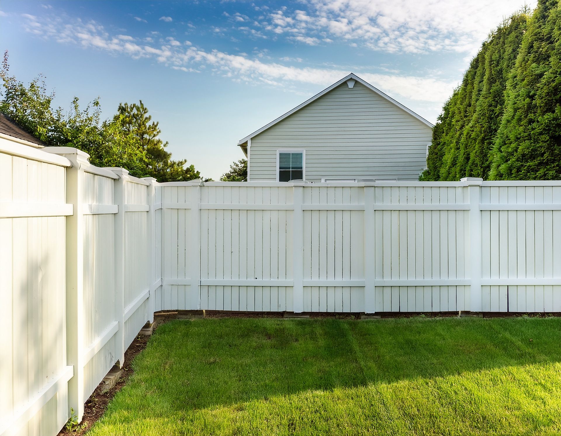 Backyard suburban home featuring a modern white fence from a top fence installation company.