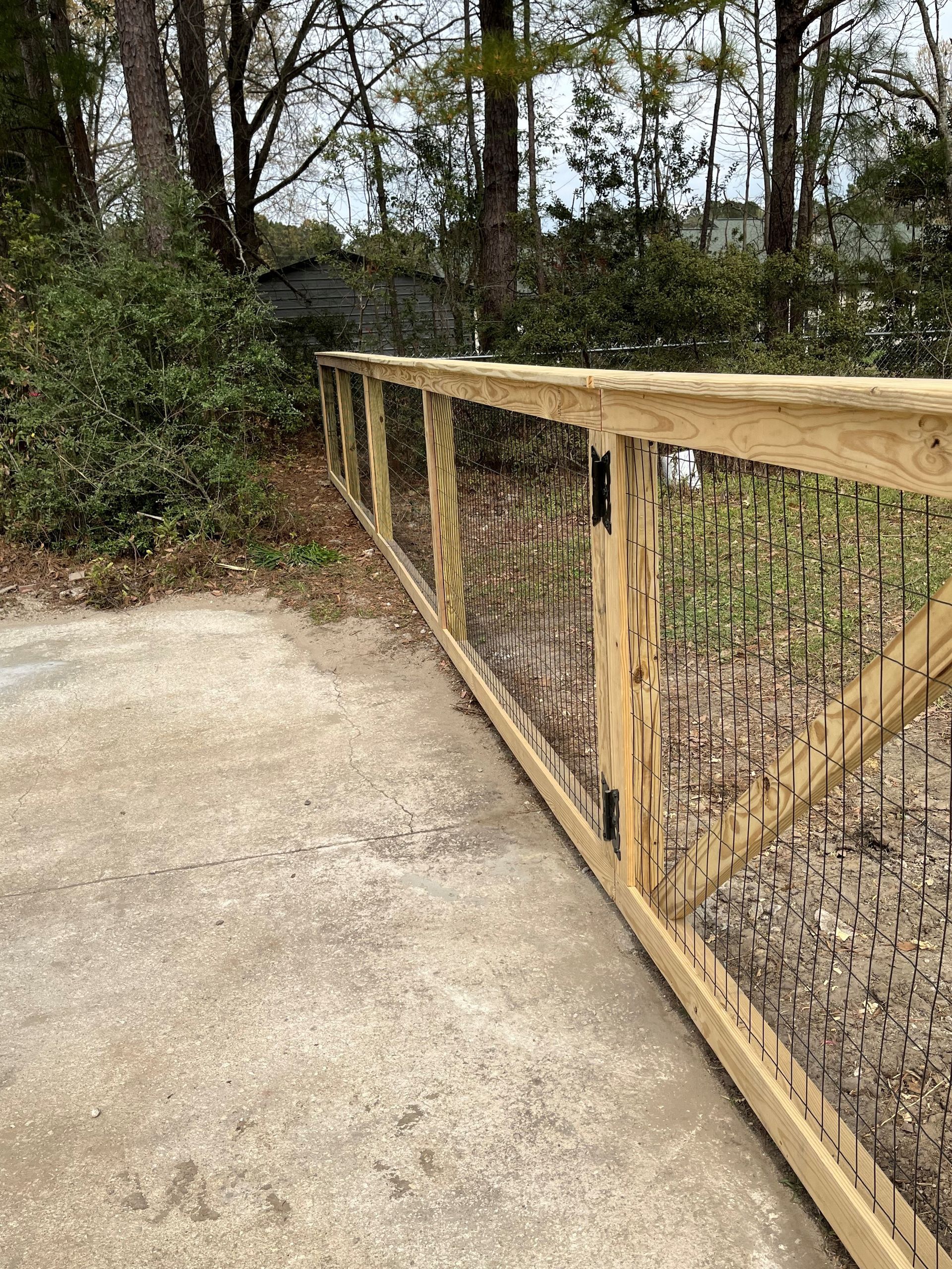 Wooden fence with wire mesh in a wooded area.