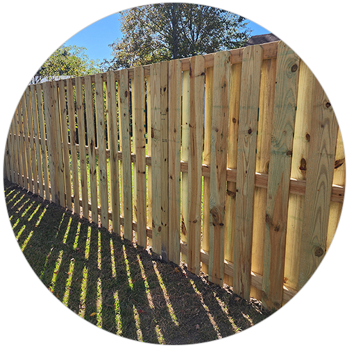Wooden fence on grass, casting long shadows. Bright sunlight.