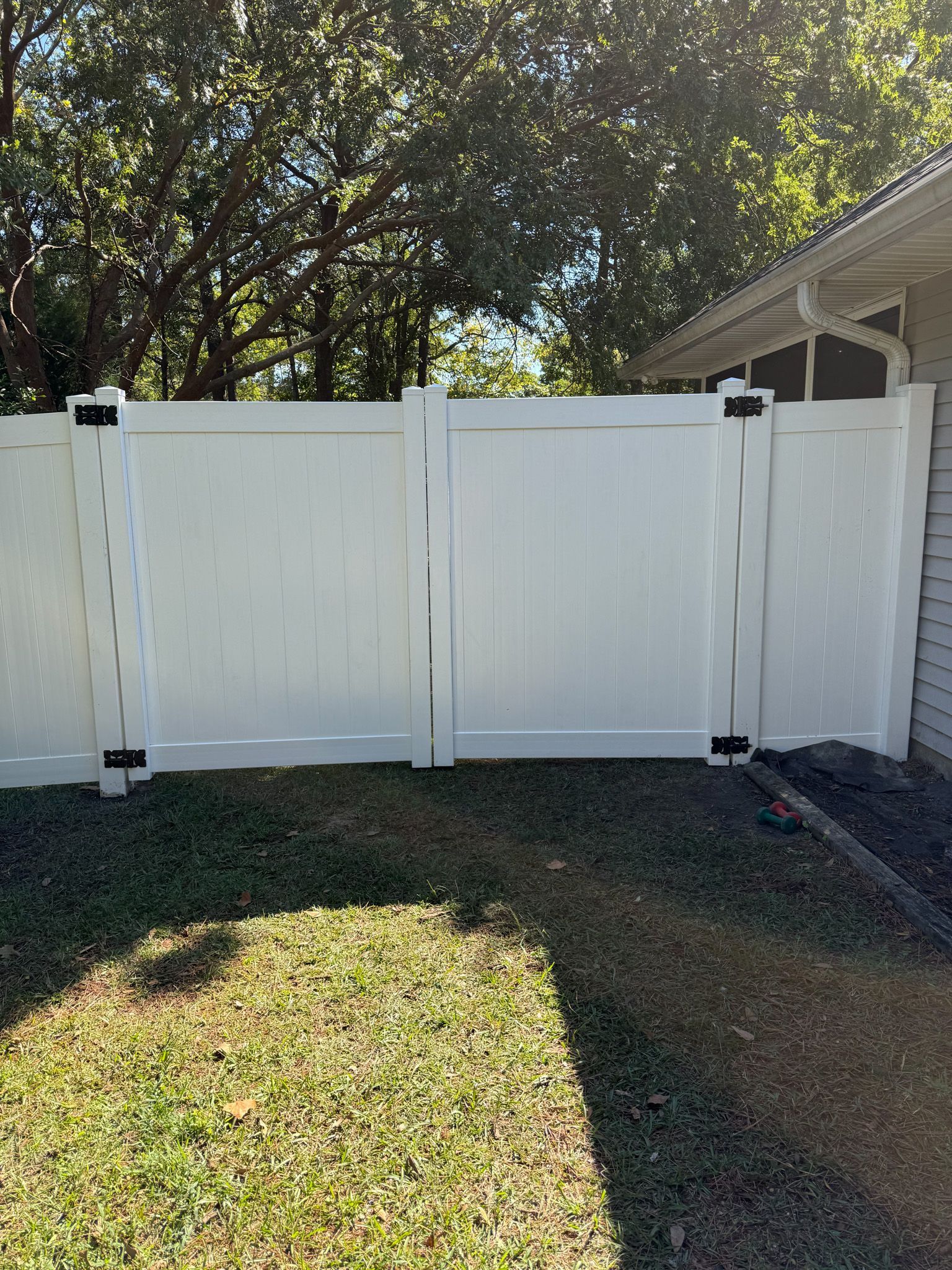 White vinyl fence with gate in a yard.