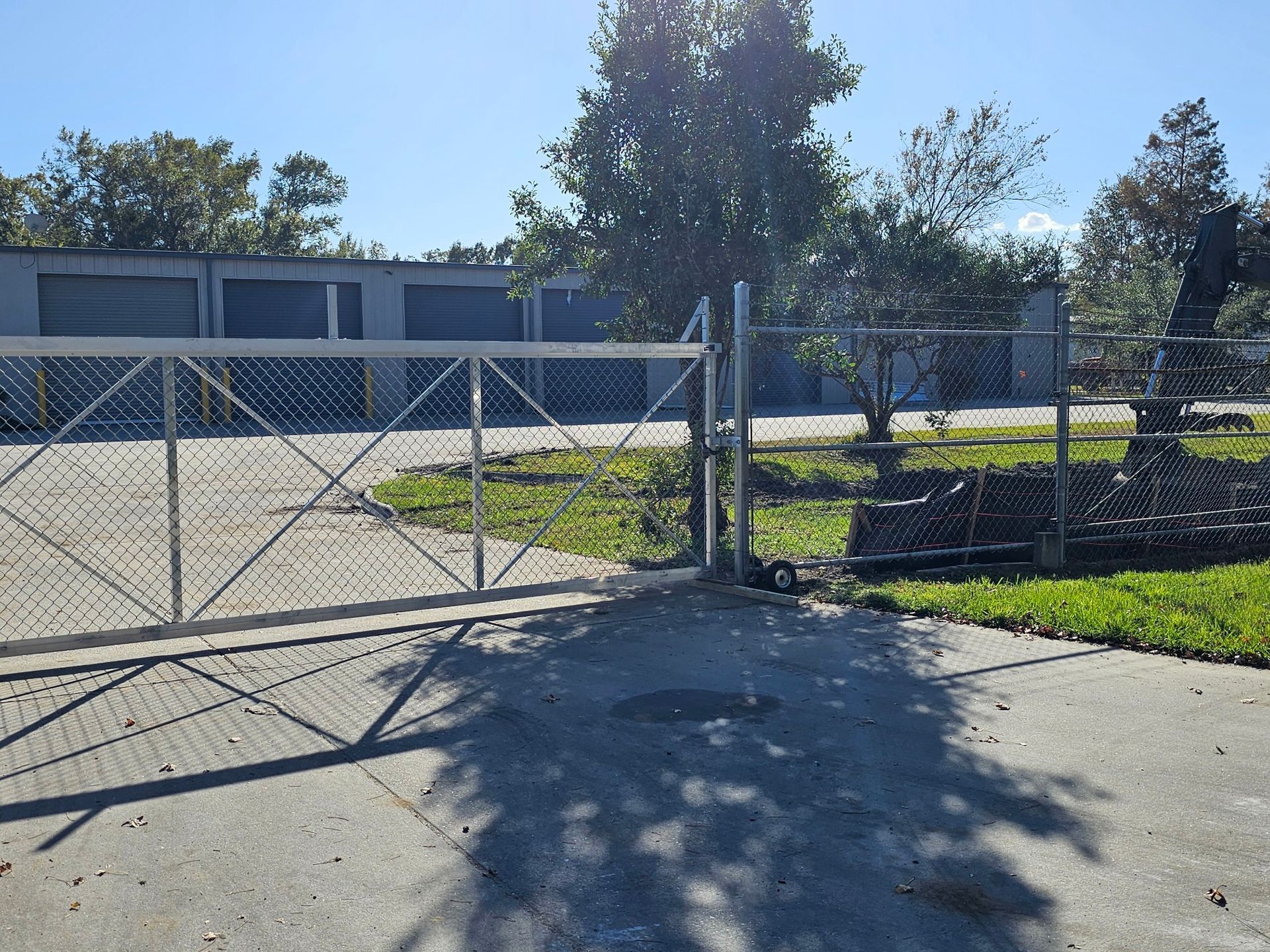 Chain link fence gate open to storage units on sunny day.