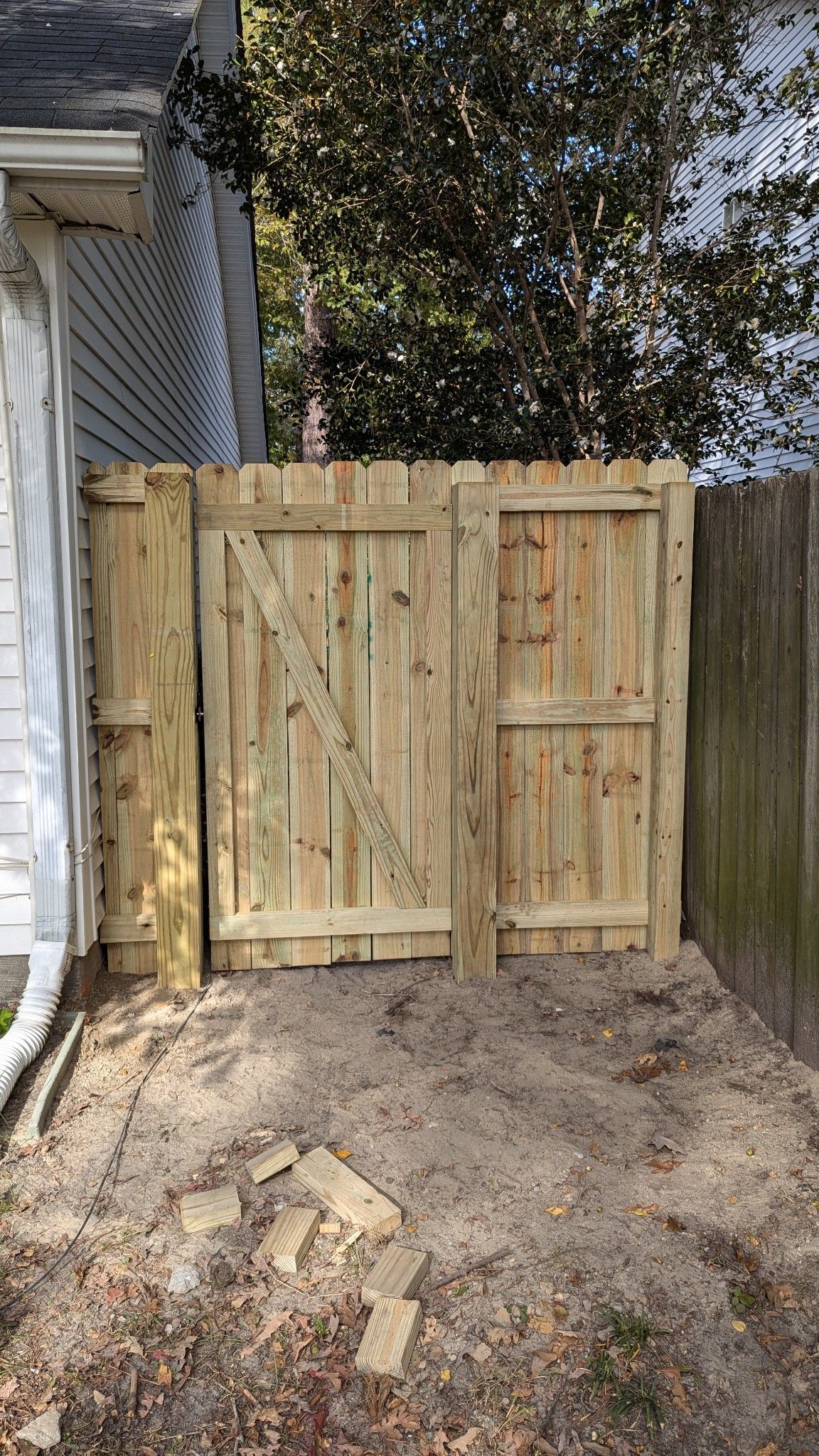 Wooden fence with three gates. Beige sand in front.