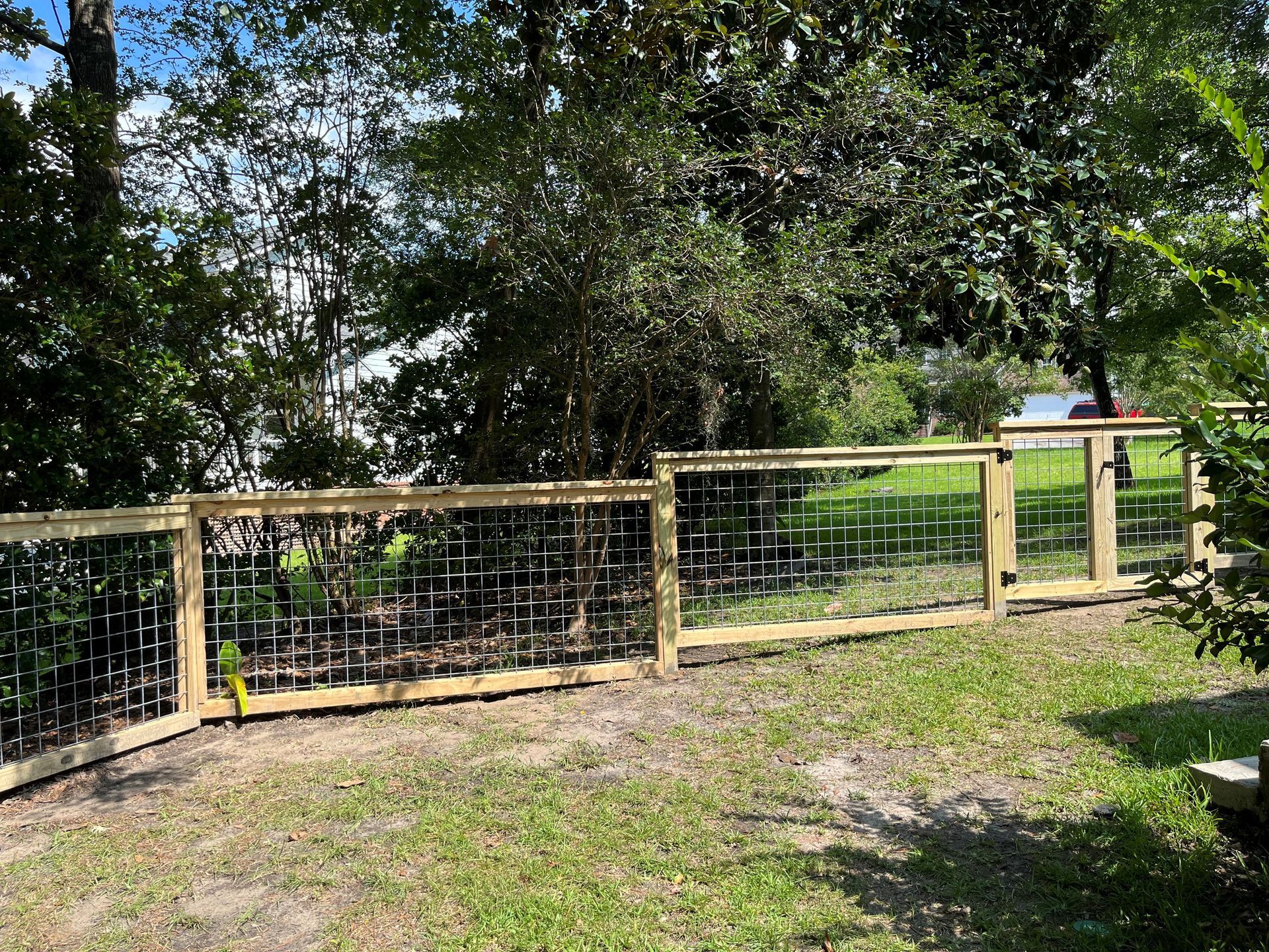 A wooden fence with intricate wire mesh design in a backyard setting.