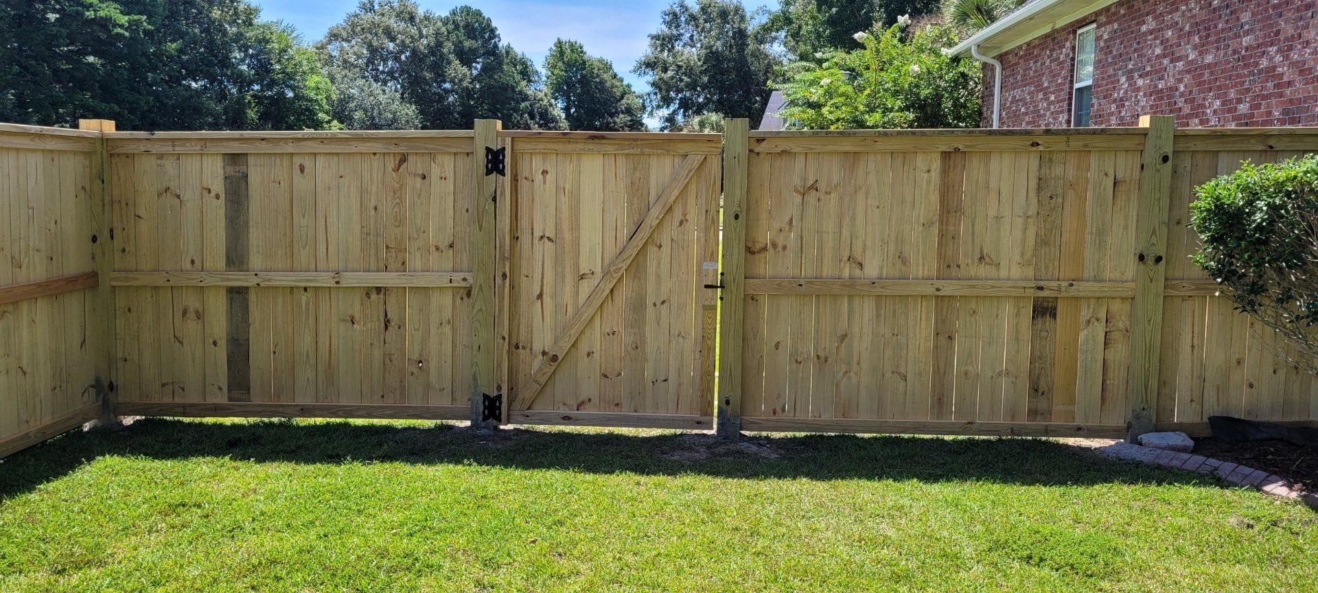 Wooden fence with gate in grassy yard.