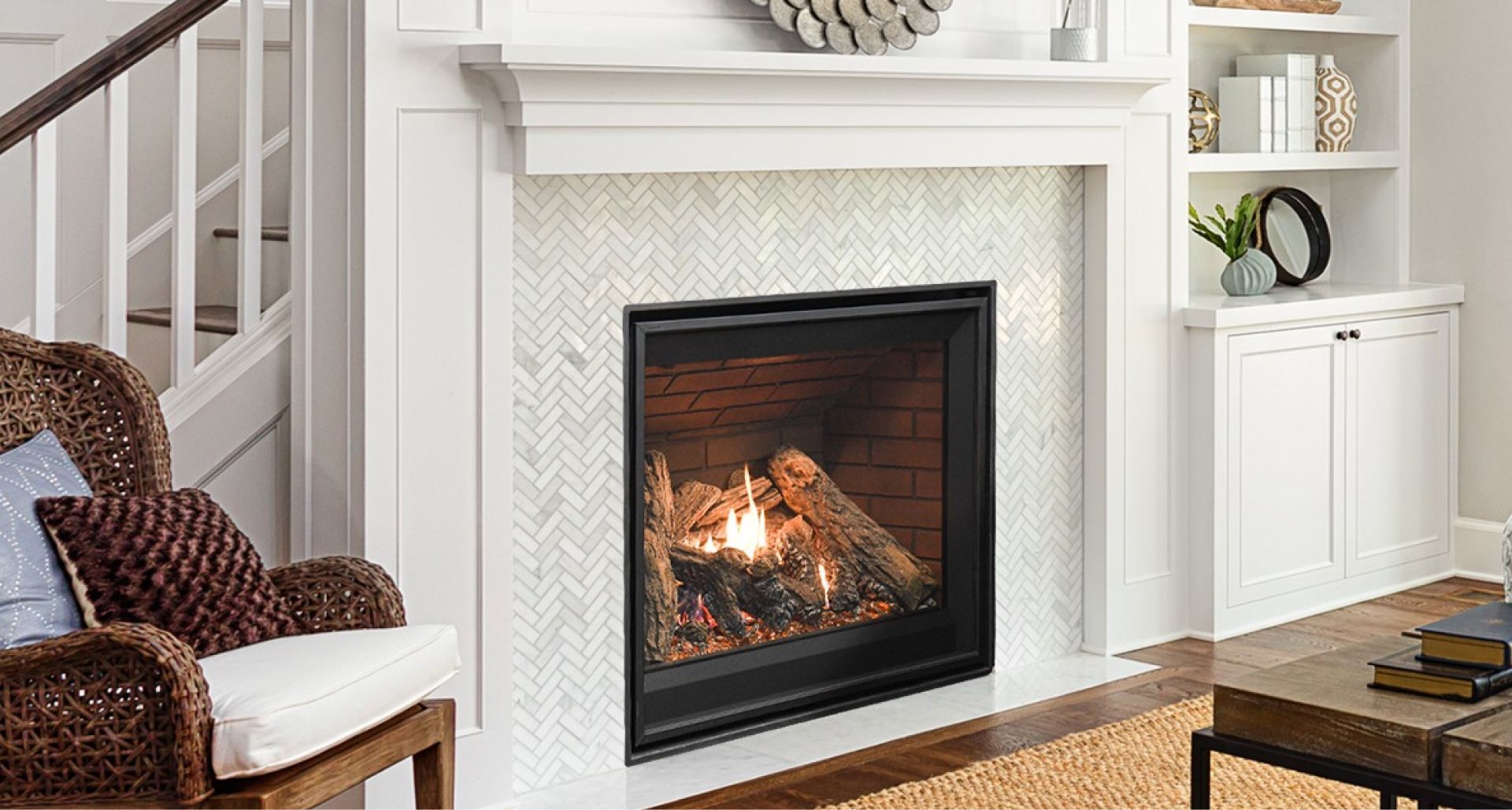 Cozy living room with a lit white fireplace, wicker chair, and built-in shelves.