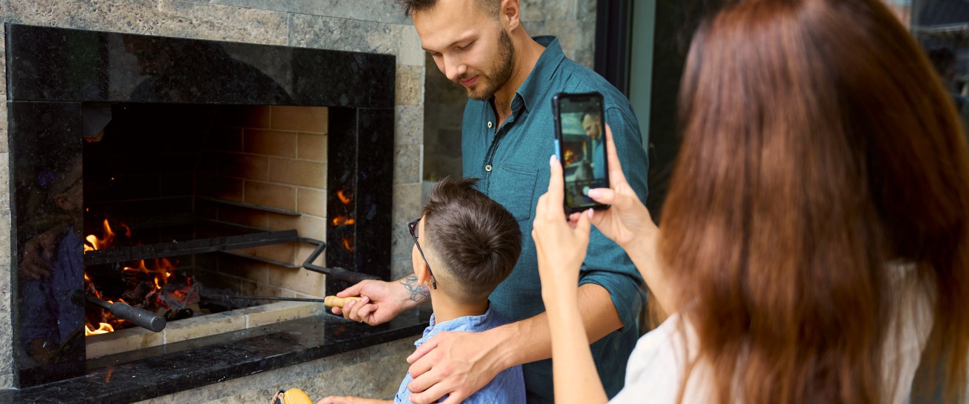 Family taking a photo of a lit fireplace with a smartphone