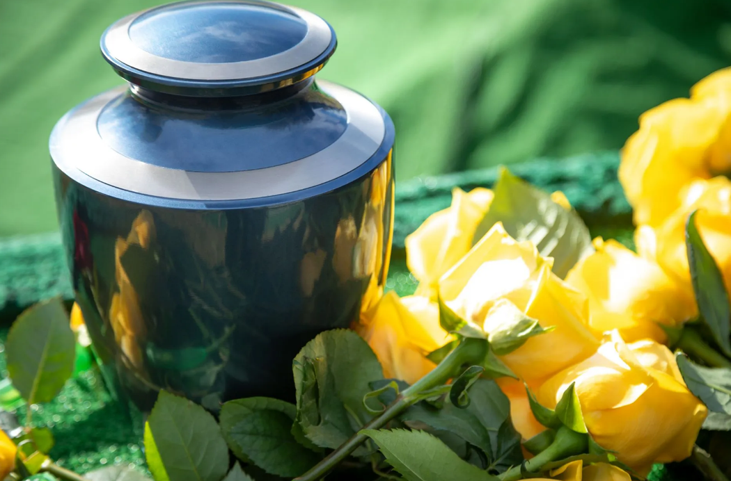 Vaso blu accanto a rose gialle su uno sfondo di tessuto verde