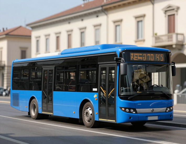 Autobus urbano blu che percorre una strada costeggiando edifici beige.