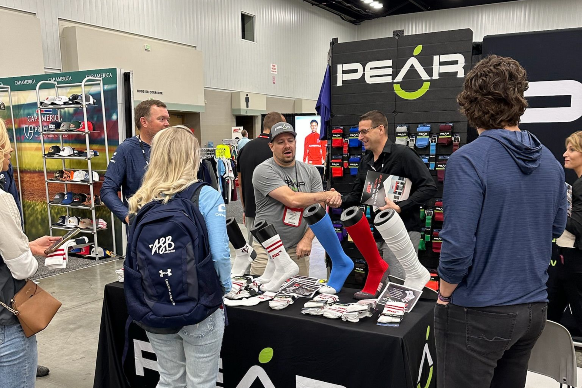 People gathered at a PEAR booth, with staff demonstrating shoes on a display table.
