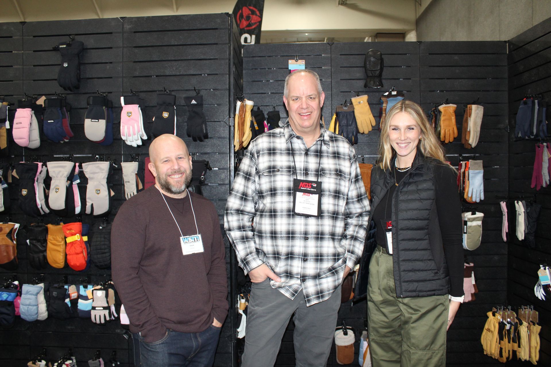 Three people posing in a retail booth with hanging socks and gear displays.