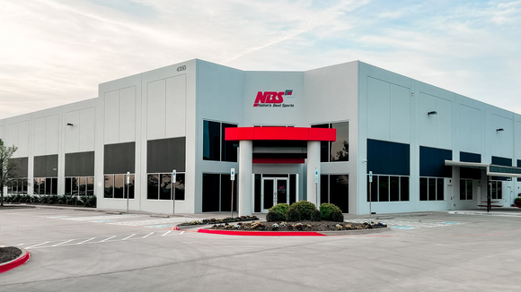 Modern white commercial building with a red awning and large windows, viewed from the parking lot