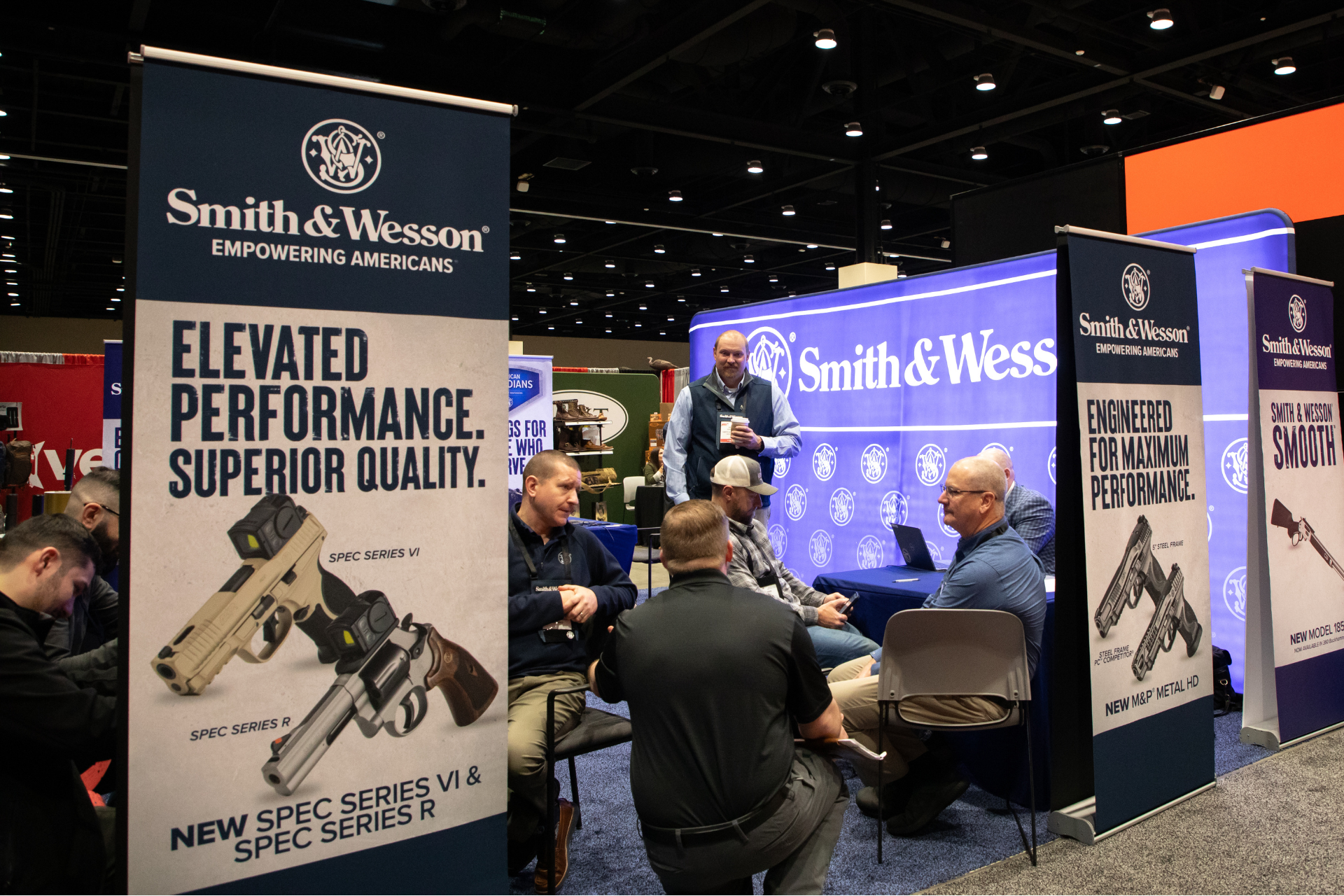 Smith & Wesson trade booth with large black banners and people talking in a convention hall