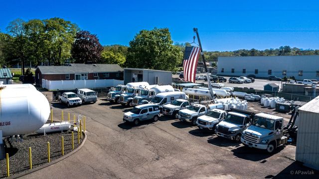 Fleet of Gas Works propane trucks with an American flag flying overhead.