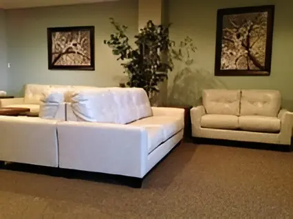 Modern living room with a white sectional sofa, cream loveseat, framed wall art, and a potted plant.