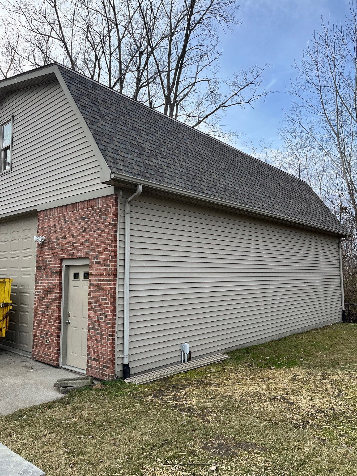 A large garage with a brick wall and a gray roof.