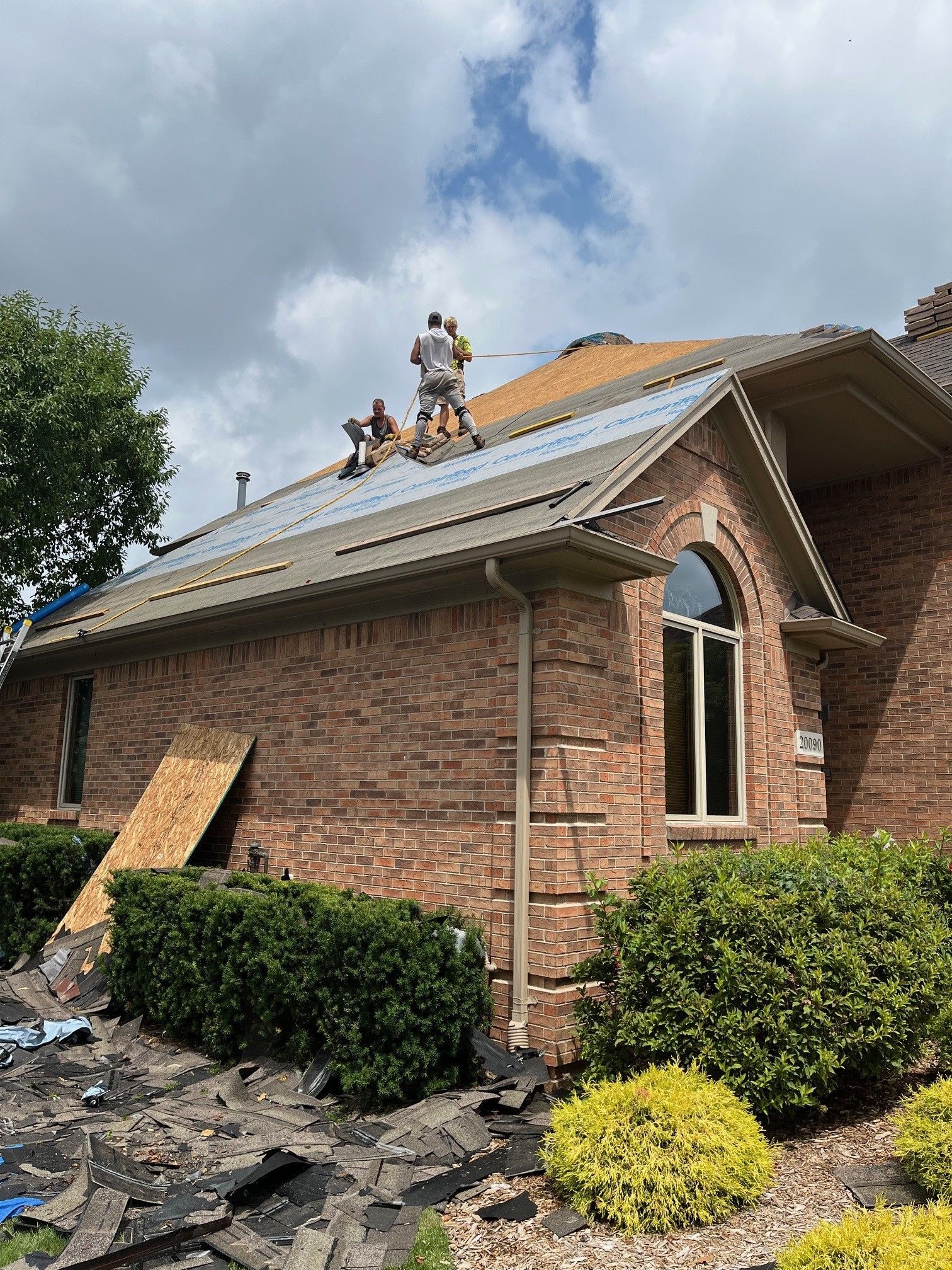 A group of people are working on the roof of a brick house.