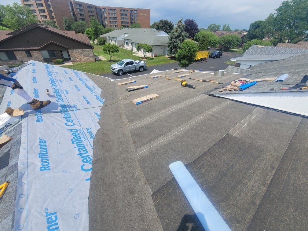 A roof is being repaired in a residential area with a truck parked in the driveway.