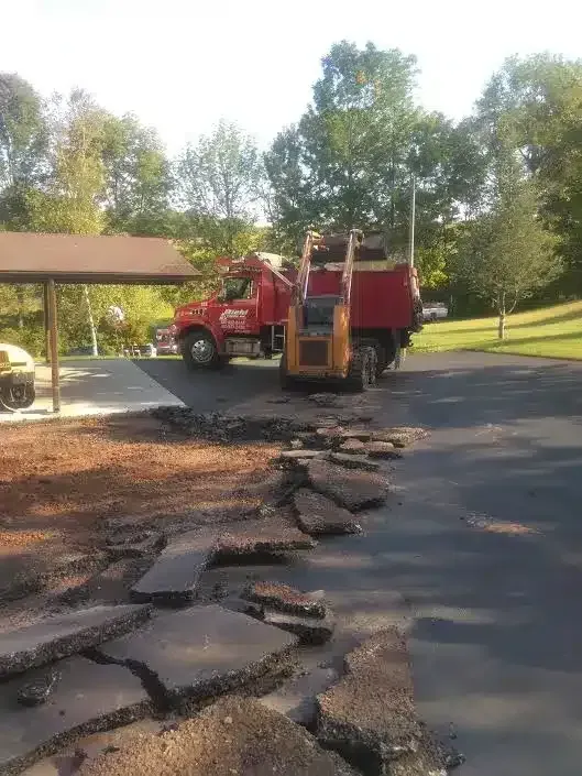 a red truck is parked in a driveway next to a bulldozer — Allentown, PA — Diehl Paving Inc.
