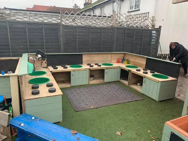 Outdoor children play Kitchen on green Astroturf.