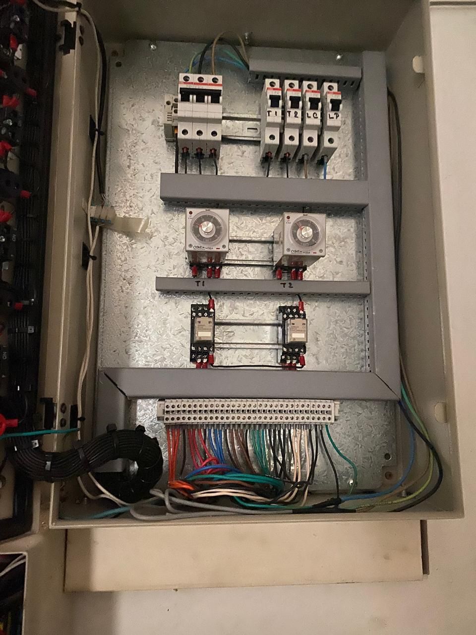 Panel de disyuntores eléctricos abierto con cableado, relés y componentes del circuito