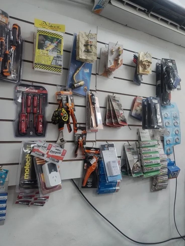 Exhibición en la pared de herramientas y accesorios empaquetados variados, colgados en ganchos en un pasillo de la tienda.