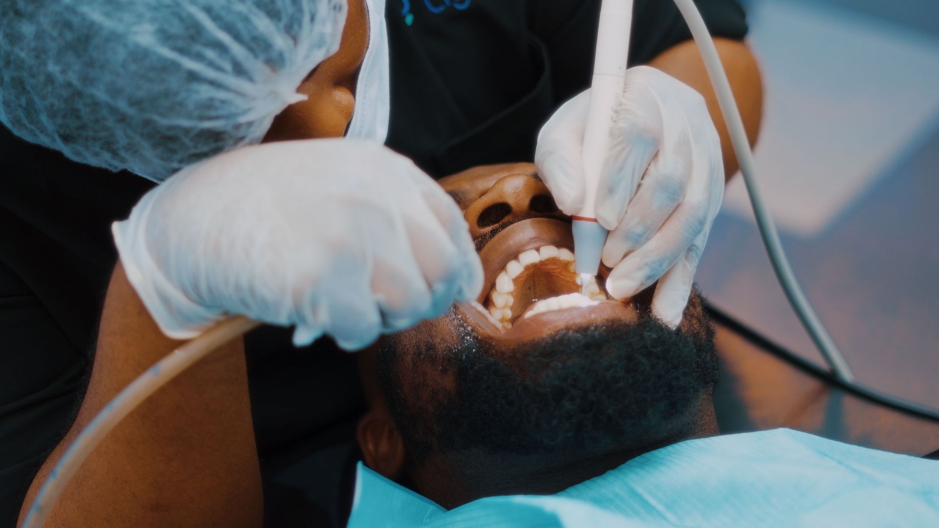 Dentist wearing gloves works on a patient’s open mouth during a dental procedure