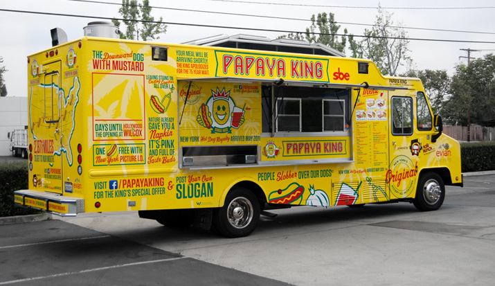 Yellow Papaya King food truck with colorful signage and open service window.